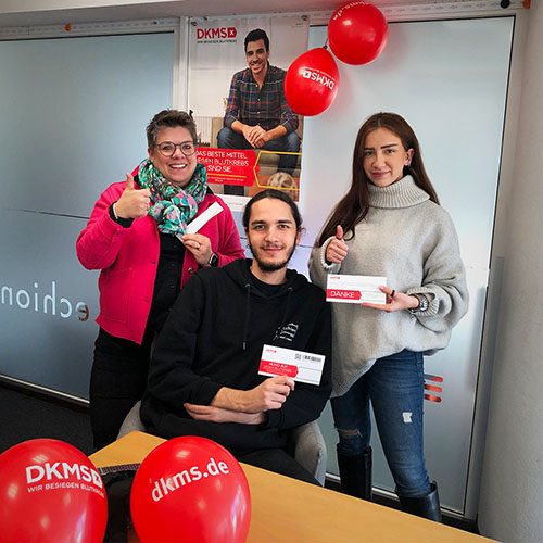 Zwei Frauen und ein Mann zeigen Daumen hoch, Luftballons mit DKMS-Logo