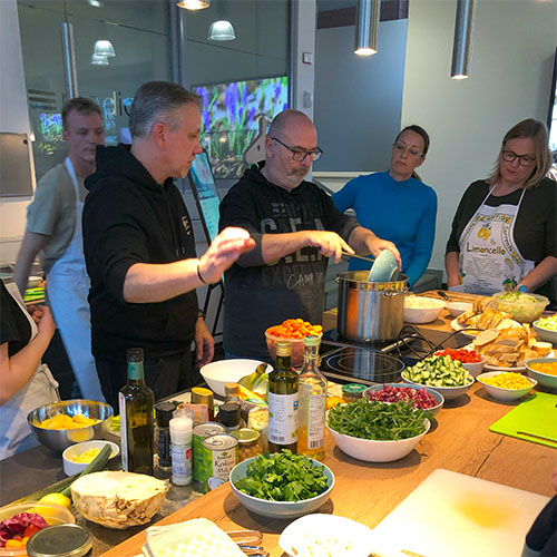 Personen beim Kochen mit Zutaten auf dem Tisch davor